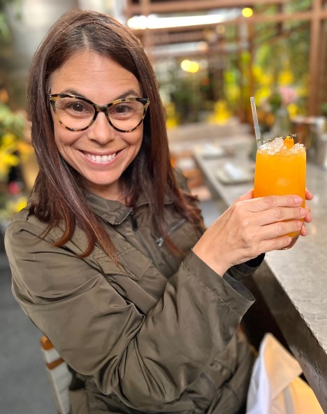 smiling woman holding orange osaka drink in lima peru