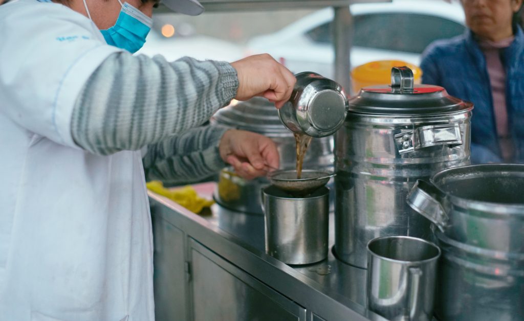Vendor preparing and serving emoliente at a street stand