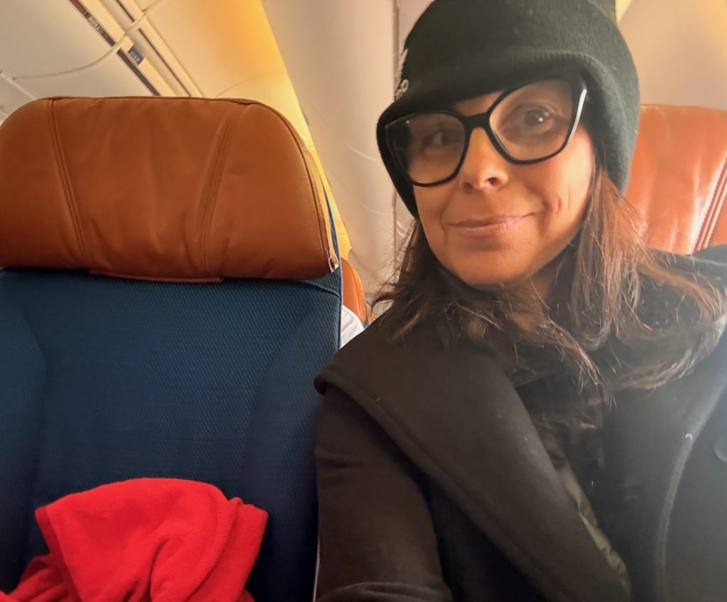 woman traveling home from a solo trip to lima peru, sitting on plane