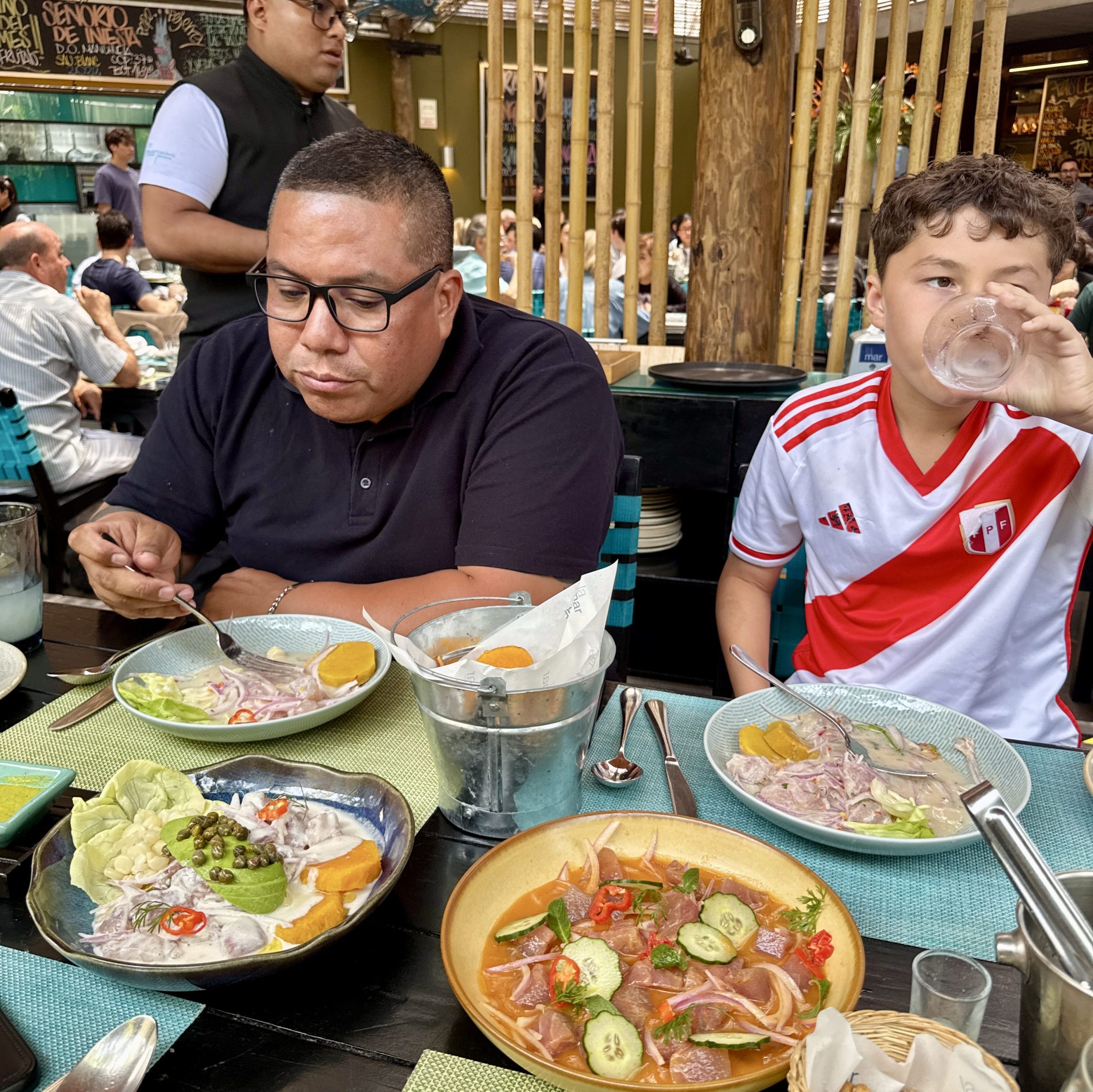 man and boy sitting in cevicheria in lima peru, enjoying ceviche