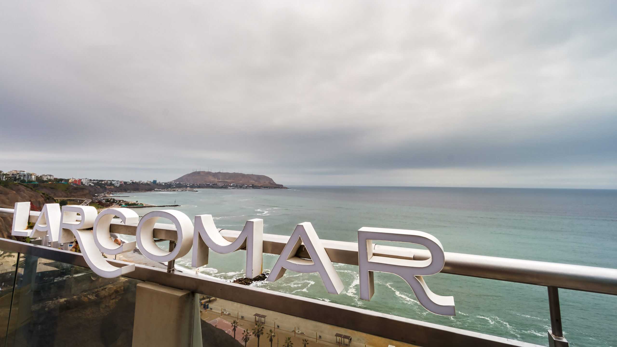 Larcomar shopping mall sign in Miraflroes district, with the sea and Chorrillos district in the background