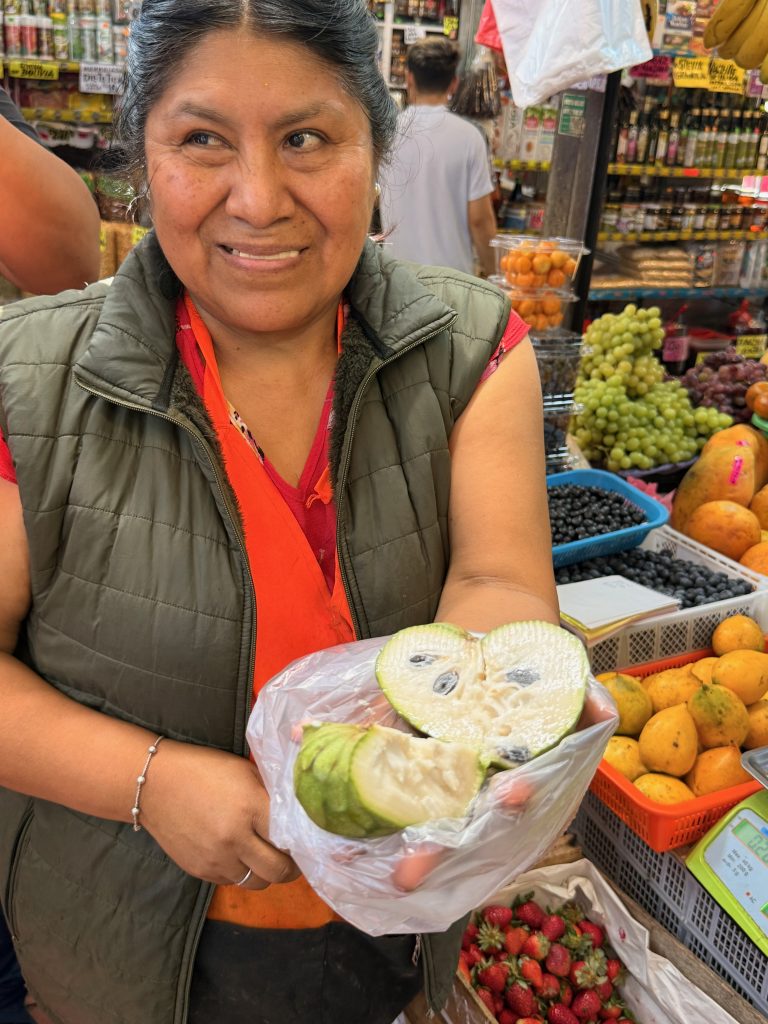peruvian market owner presenting freshly sliced Cherimoya