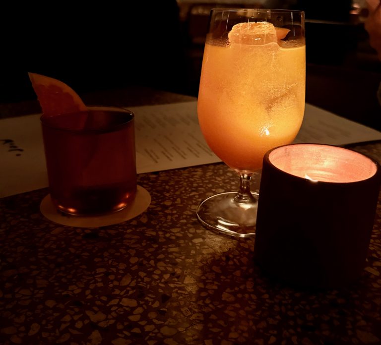 drinks next to candlelight on a moody, atmospheric restaurant
