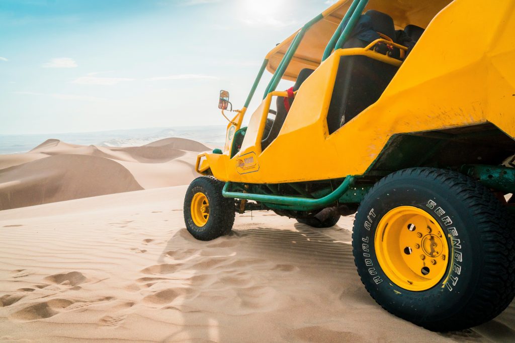 close up of yellow and green dune buggy in sand dunes