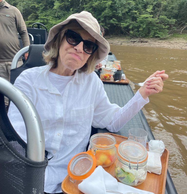 happy woman sitting in boat on the amazon, enjoying poached eggs with fresh avocados and a fruit parfait