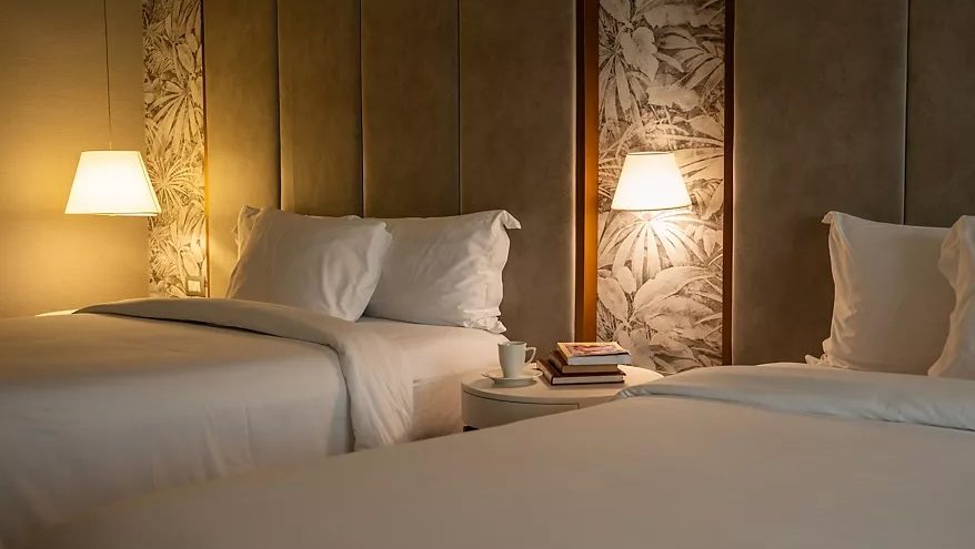 Manto Hotel Lima – MGallery — A guest room, with its warm lighting and botanical-print headboards.