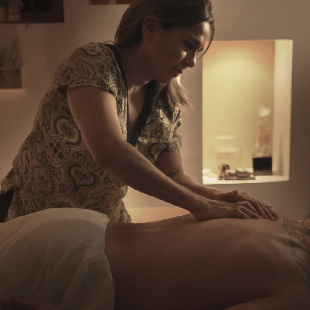 massage therapist rubbing back of client at salon spa