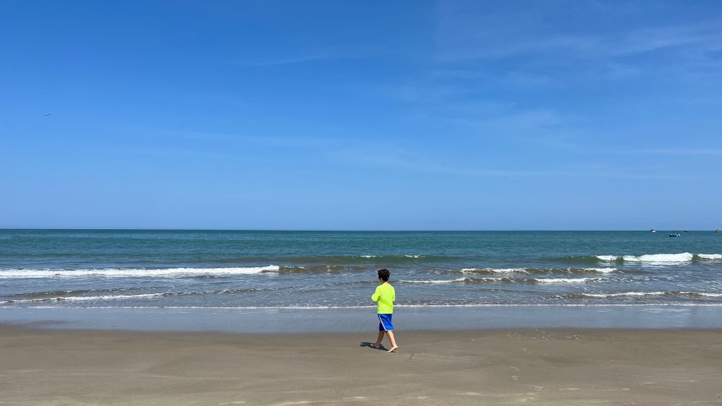young boy walking along a northern peruvian beach